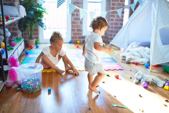 Beautiful toddlers playing around lots of toys at kindergarten