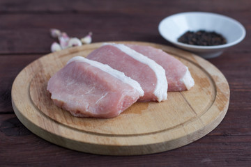 Fresh raw meat on a wooden Board.Pork escalope for frying or cooking chops.