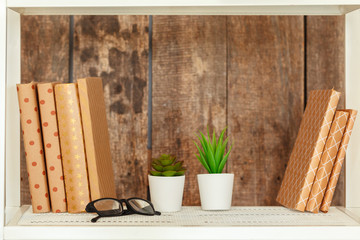 Stylish white bookshelf against grunge wooden wall