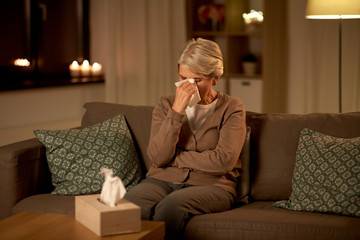 sadness, stress and people concept - unhappy crying senior woman wiping tears with paper tissue at home at night