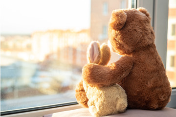 Pair of toys. Bunny and teddy bear  Embracing loving teddy bear toy and bunny sitting on window-sill