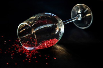 concept spilled red wine. end of the party. a glass of wine lying on a table in it red stars symbolizing spilled wine