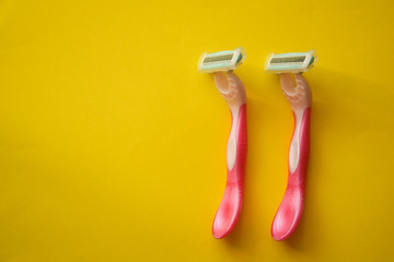 New pink disposable razors for safe shaving of female skin with selective focus on yellow background with copy space. Razor for smooth shaving. Sharp razors for personal hygienic routine 