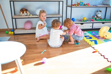 Adorable toddlers playing around lots of toys at kindergarten