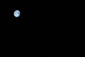 A distant round moon on a black background .Texture or background