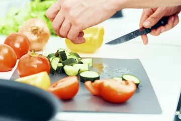 Fotobehang woman cutting vegetables in kitchen © SHOTPRIME STUDIO