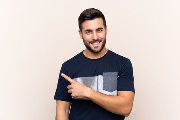 Young handsome man with beard over isolated background pointing to the side to present a product