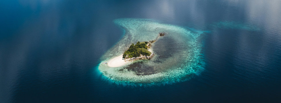 Aerial view of small tropical island with white sand beach, Beautiful clouds reflections in water surface. Tropical background.