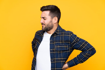 Young handsome man with beard over isolated yellow background suffering from backache for having made an effort