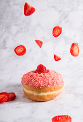 Strawberries falling on doughnut with white background