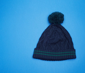 dark blue knitted hat with pompom on a blue background