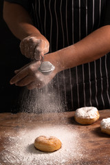Fototapeta premium Master Chef's hands sprinkling sugar powder over homemade donut. Selective focus.