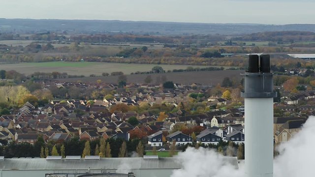 UK houses dominated by a factory. Conceptual aerial shot of homes and industry.