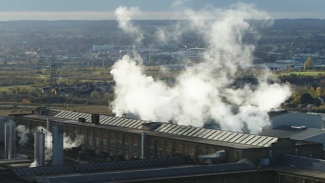 Aerial view steam being blown from a Victorian paper mill dominating over houses in the UK