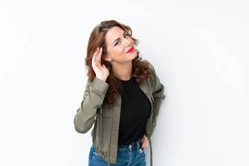 Young Russian woman over isolated white background listening to something by putting hand on the ear