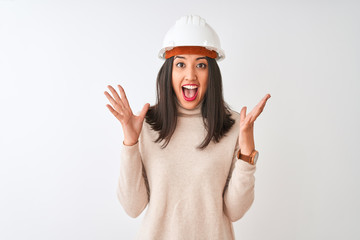 Young chinese architect woman wearing security helmet over isolated white background celebrating...