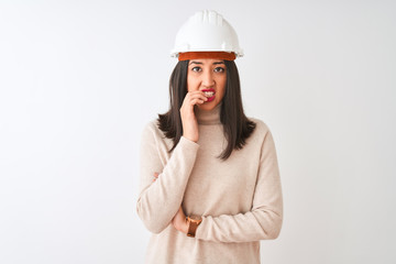 Young chinese architect woman wearing security helmet over isolated white background looking stressed and nervous with hands on mouth biting nails. Anxiety problem.