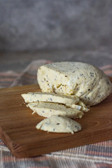 Rustic home-made cheese on a gray stone background, vertical arrangement
