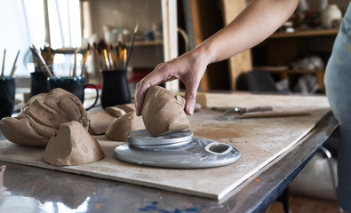 The Potter kneads a piece of clay with his hands and weighs it on the scales.