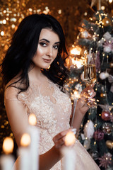 Sexy model girl with glass of champagne at party, drinking champagne over holiday glowing background. Beauty woman with perfect fashion makeup. Christmas and New Year holiday celebration