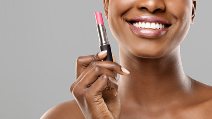 Beautiful afro girl holding pink lipstick in hand and smiling - obrazy, fototapety, plakaty