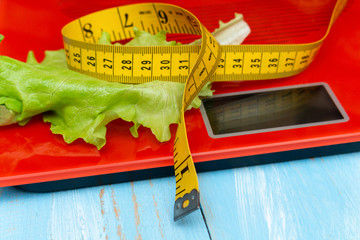 digital electronic scale with measuring tape, lettuce. diet, slimming concept.