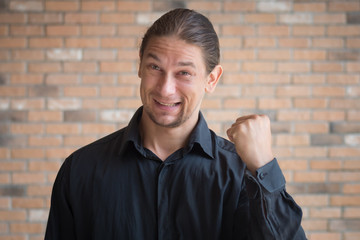 successful happy smiling positive business man pointing up finger to space; concept of success, successful business, goal achievement by smart casual caucasian man