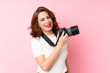 Obraz premium Young Russian woman over isolated pink background with a professional camera