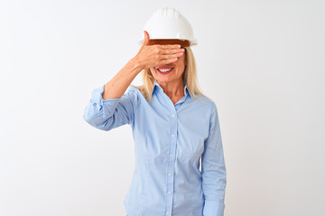 Middle age architect woman wearing glasses and helmet over isolated white background smiling and laughing with hand on face covering eyes for surprise. Blind concept.
