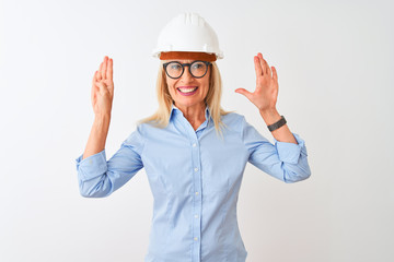 Middle age architect woman wearing glasses and helmet over isolated white background showing and pointing up with fingers number nine while smiling confident and happy.