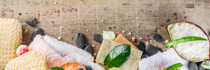Bodycare organic cosmetics. Spa setting with basic hygiene treatment - sea salt, washcloth and natural handmade soap, and bath stuff ready for use. Zero waste bath care concept. Wooden background