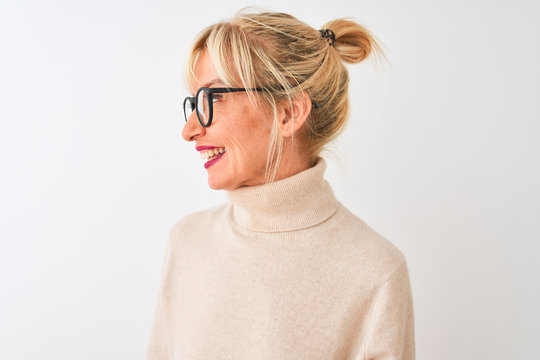 Middle age woman wearing turtleneck sweater and glasses over isolated white background looking away to side with smile on face, natural expression. Laughing confident.