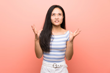 Teenager asian girl over isolated pink background frustrated by a bad situation