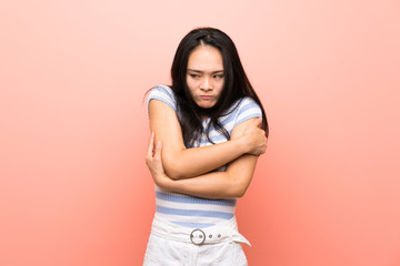 Teenager asian girl over isolated pink background freezing