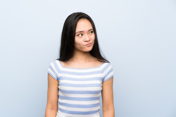 Fototapeta premium Teenager asian girl over isolated blue background standing and looking to the side