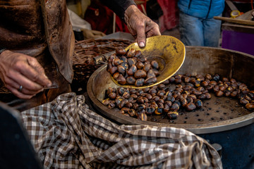 Roasted chestnuts seller putting chestnuts on a plate