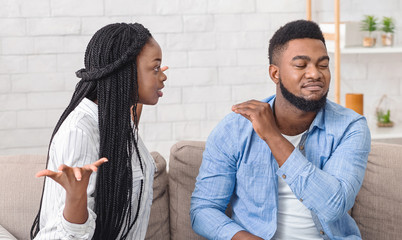 Black couple quarreling at home, wife blaming husband