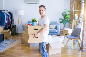 Fototapeta na wymiar Young handsome man moving cardboard boxes at new home