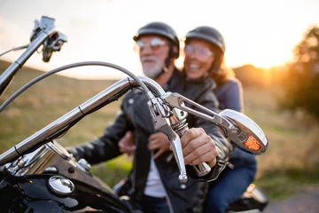 Tuinposter Cheerful senior couple travellers with motorbike in countryside. © Halfpoint