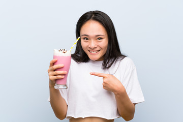 Teenager asian girl holding a strawberry milkshake with surprise facial expression