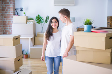 Fototapeta na wymiar Young beautiful couple standing at new home around cardboard boxes