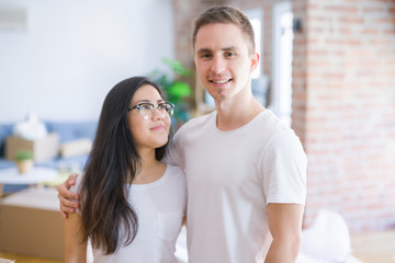 Fototapeta premium Young beautiful couple standing at new home around cardboard boxes