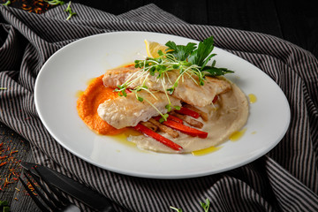 Grilled pike perch with vegetables and sauce. Restaurant menu. Background black boards.