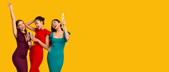 Three Elegant Girls Dancing With Champagne Over Yellow Background, Panorama