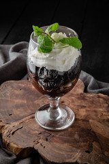 Prunes with nuts with cream and mint in a glass cup. Healthy dessert made from dried fruits. Restaurant menu. Background black boards.