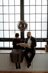 A loving couple a man and a woman exchange Christmas gifts at home.