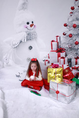 little girl with snowball and snowman with gifts