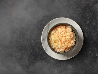 homemade fermented cabbage in a bowl. healthy vegan salad. dark concrete background, top view