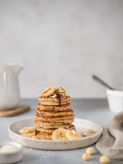 banana pancakes with nuts and syrup. healthy breakfast. gray background, vertical image.