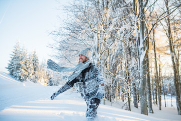 Young man having fun in snow outdoors in winter.